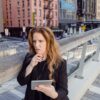 businesswoman leaning against railing in a city and calculating business risk