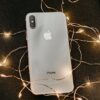 silver iphone x lying on pre lit string lights