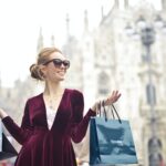 woman wearing maroon velvet plunge neck long sleeved dress while carrying several paper bags photography